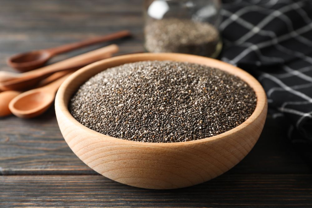 Chia in wooden bowl on wood background, close up