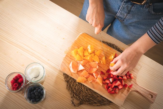 Crop woman cutting fruits for smoothie