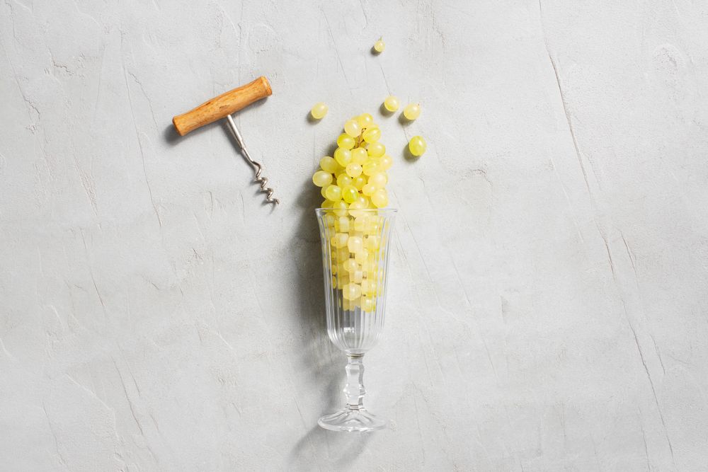 Wineglass filed with grapes on gray background