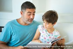 Dad with girl reading together at home bxJ8a5