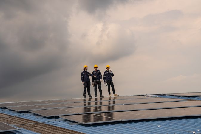 Engineer team checking solar cell  or photovoltaic cell installed on the roof of the factory. Technician worker repair or inspect the system. Industrial renewable energy concept