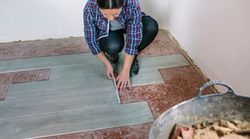 Female bricklayer measuring tiles to install a floor