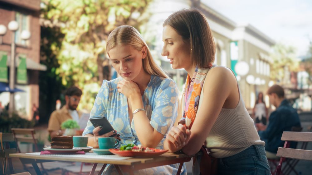 Female Friends Having a Fun Conversation and Browsing Internet and Online Social Networks on a Smartphone Device