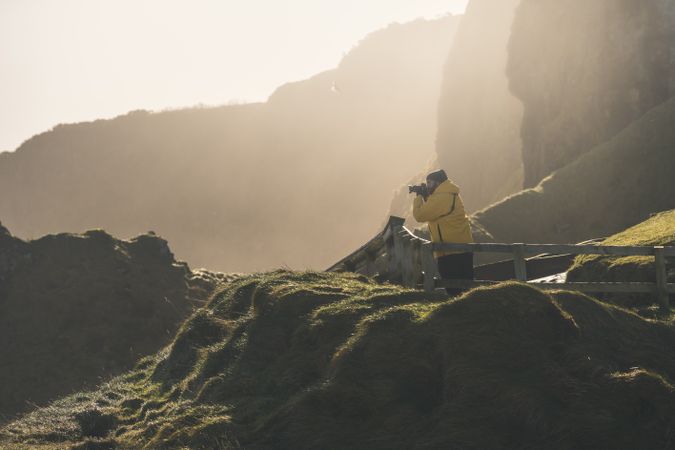 Man standing on country road and taking picture of sea with camera