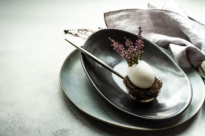 Elegant Easter table with heather and egg decor on dark plate with space for text