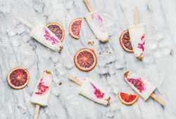Blood orange home-made ice pops laying on marble