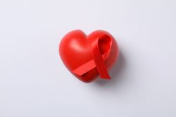 AIDS awareness red ribbon and heart on blank background, space for text