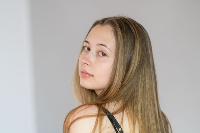 Studio portrait of blonde teenage girl in dark strap top