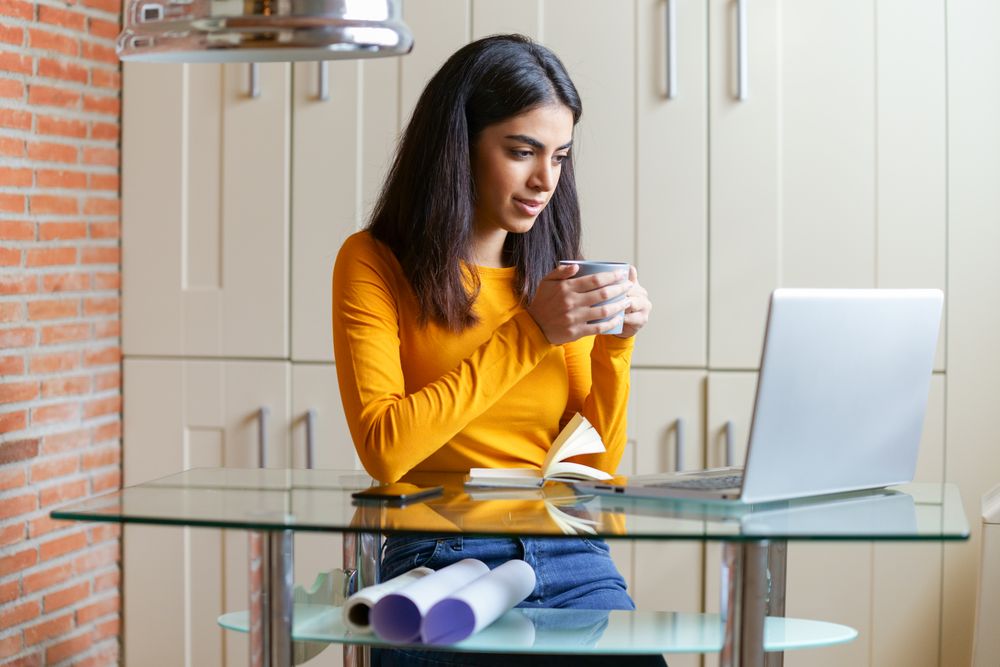 Persian woman working at home with a laptop and blueprints underneath her desk