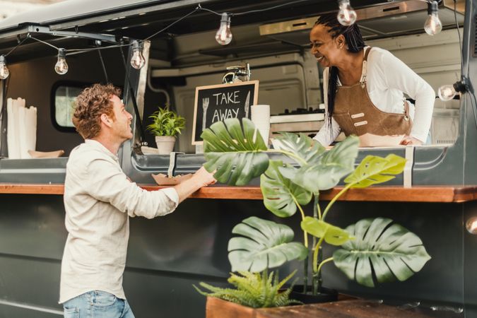 Chef woman taking order from customer at food truck outdoor - Focus on man face