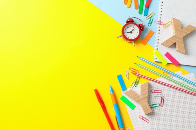 Flat lay composition with school supplies on two tone background, space for text