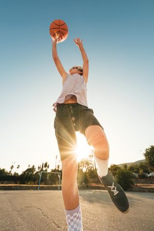 Energetic kid jumping while throwing ball