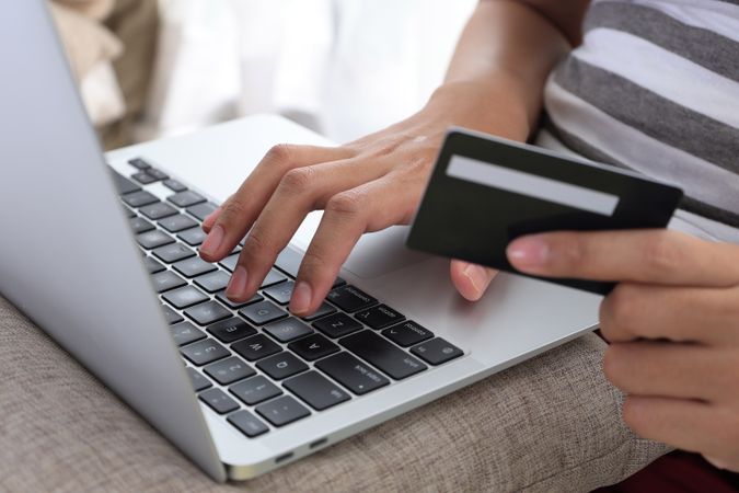 Female Hands Holding Credit Card and Using Laptop.