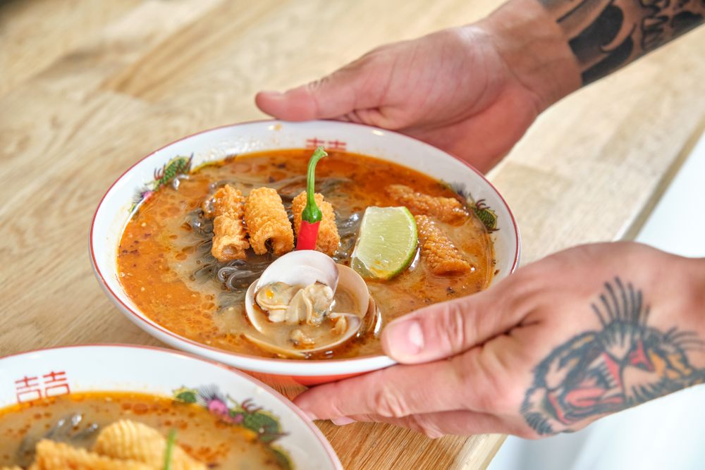 Man serving noodle soup on wooden table