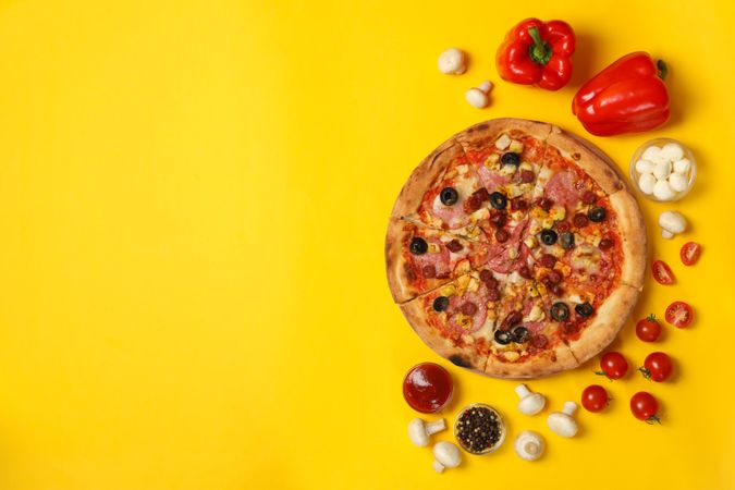 Tasty pizza and ingredients on yellow background