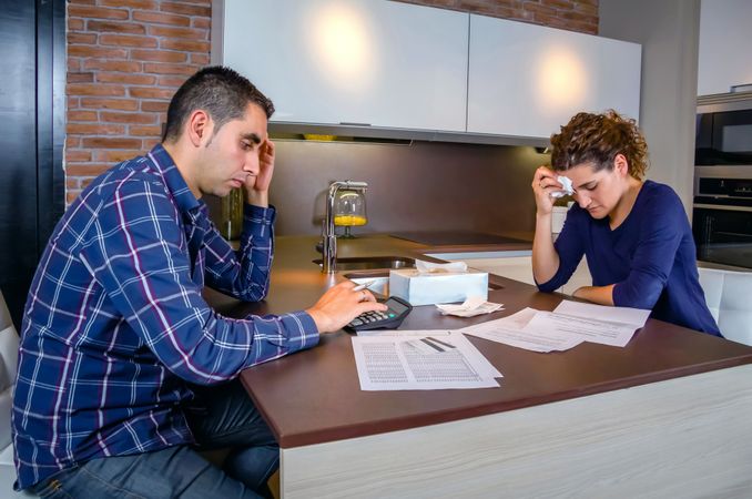 Couple with their heads down as they have tense discussion over bills