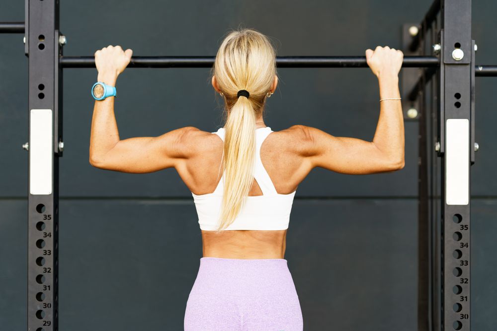 Back of fit woman doing pull ups on bar