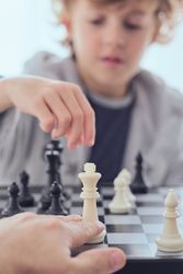 Anonymous person playing chess with boy
