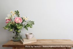 Table with cup of tea and vase of pink flowers 49jvWb