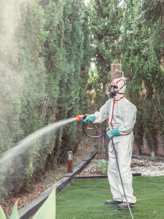 Fumigator in uniform spraying substance on garden
