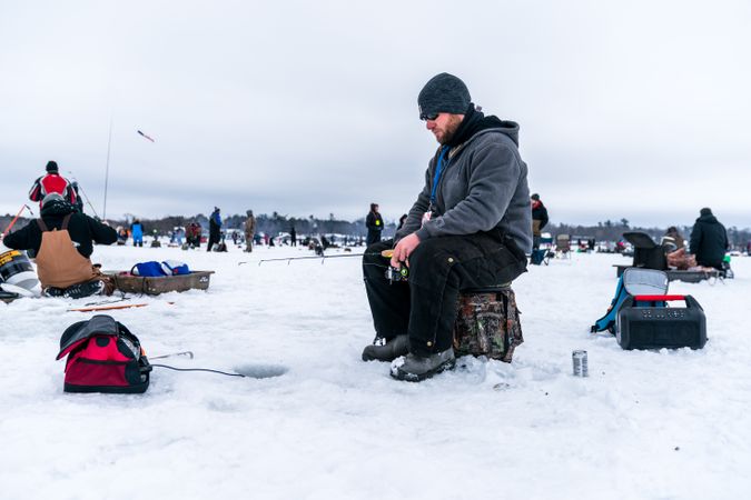 Nisswa, MN, USA - January 25th, 2020: Man sitting with fishing rod ice fishing on a frozen lake
