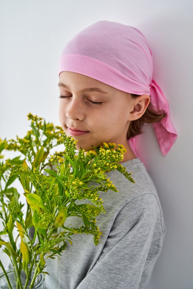 Kid in pink headband enjoying smell of wildflowers