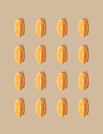 Pattern of orange fruit slices and pastel sand background