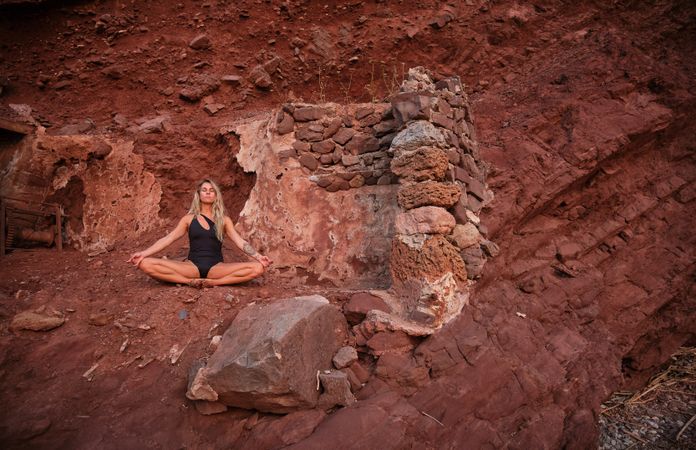 Woman sitting on top of rock and practicing yoga