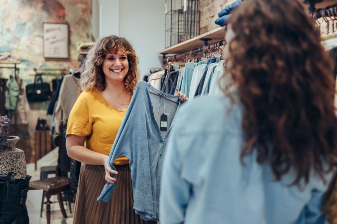 Woman working in a fashion retail shop assisting shopper