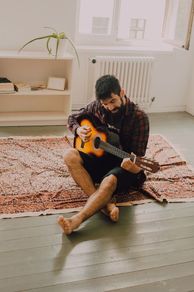 Relaxed bearded man playing guitar at home