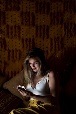 Smiling woman using smartphone in dark room