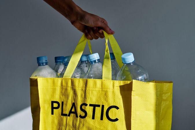 Volunteer carrying bag with plastic bottles for reuse