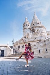 Laughing women in colorful dress dancing against old building