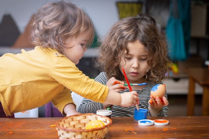 Sisters painting Easter eggs at home
