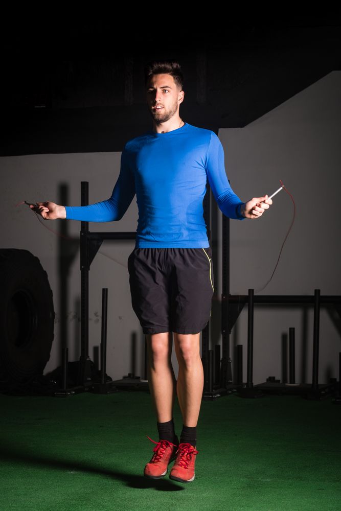 Man exercising with jump rope in gym