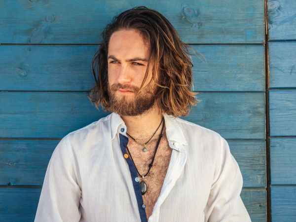 Cheerful guy sitting near blue wall