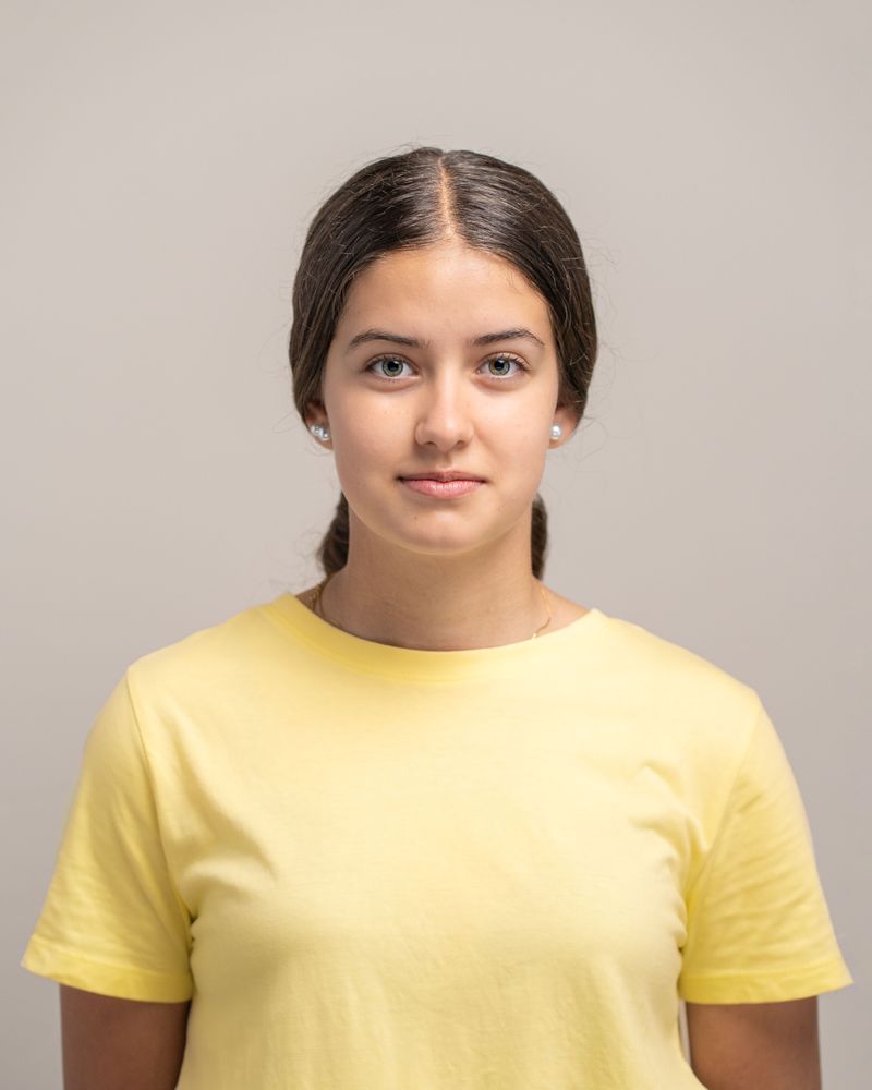 Headshot portrait of a beautiful young woman with a neutral expression looking at the camera.