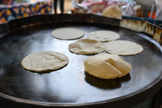 Delicious corn tortillas cooking on griddle