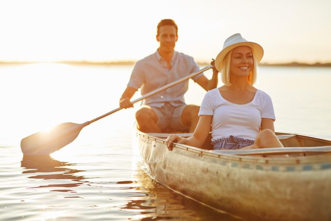 Blonde woman relaxing in canoe while man paddles