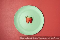One strawberry cut in half on green plate 4mDJe5