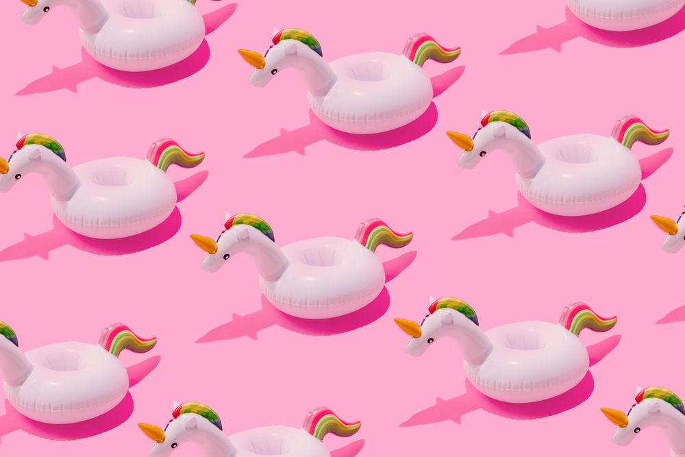 Inflatable unicorn pool toy pattern on pastel pink background