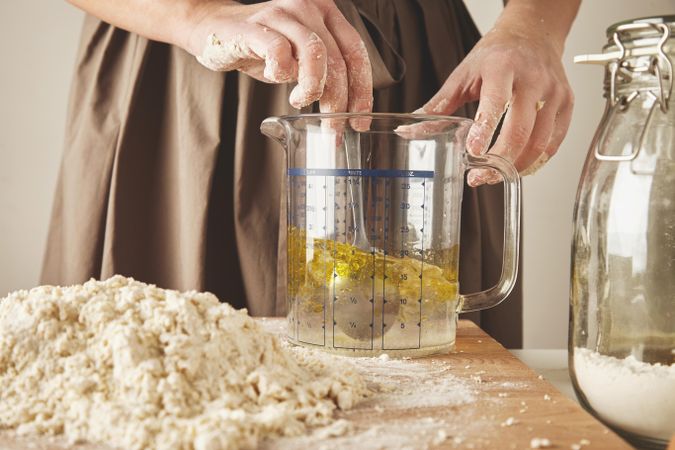 Woman combining olive oil and water in measuring cup