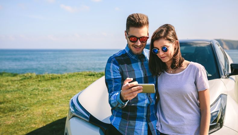 Couple with car looking mobile