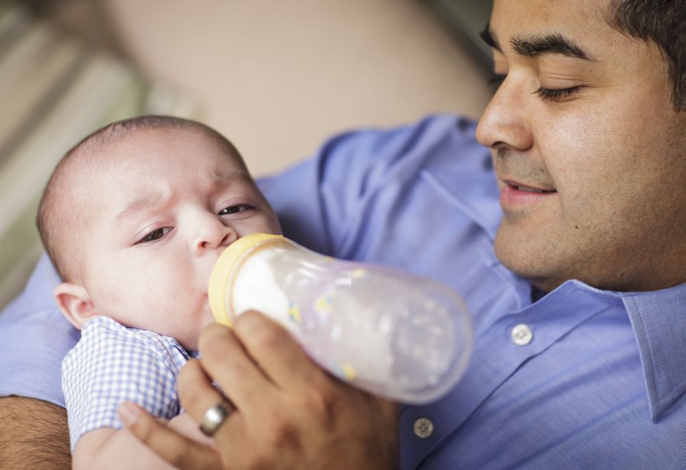 Happy Hispanic Father Bottle Feeding His Son