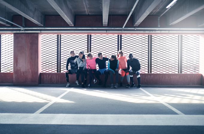 Group of sporty people sitting against a barred window talking with each other