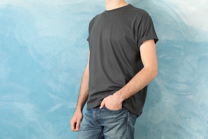 Men in blank grey t-shirt against blue background, space for text
