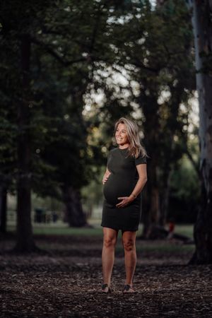 Charming pregnant woman standing on walkway in park