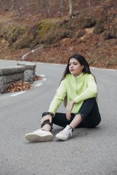 Woman in sweater sitting on asphalt road