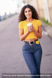 Female in yellow t-shirt walking on street with coffee, vertical composition 0P7yNb