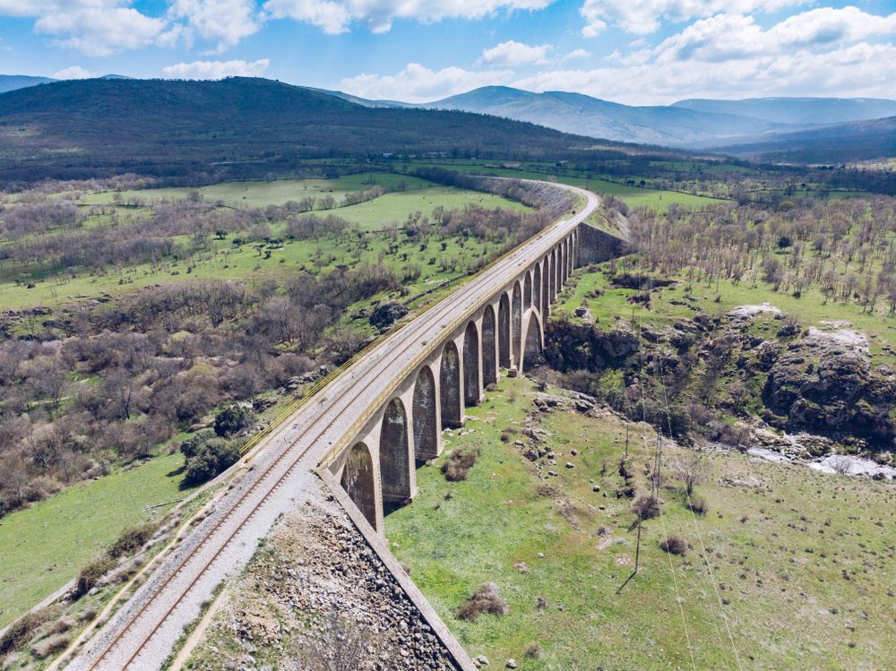 Concrete bridge over mountain river at picturesque green valley